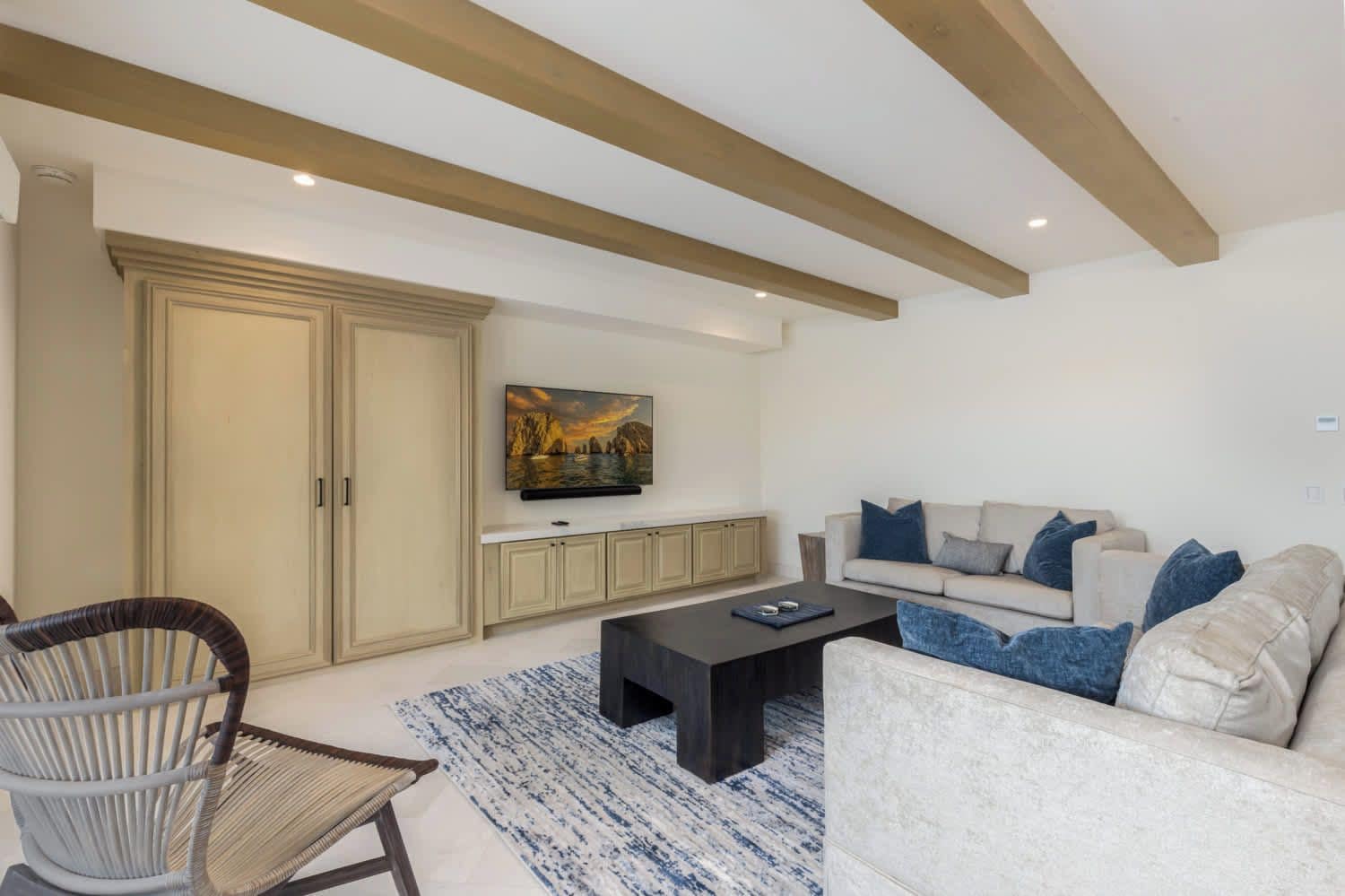 A modern living room with a sofa, a coffee table, a TV mounted on the wall, and a large cabinet.