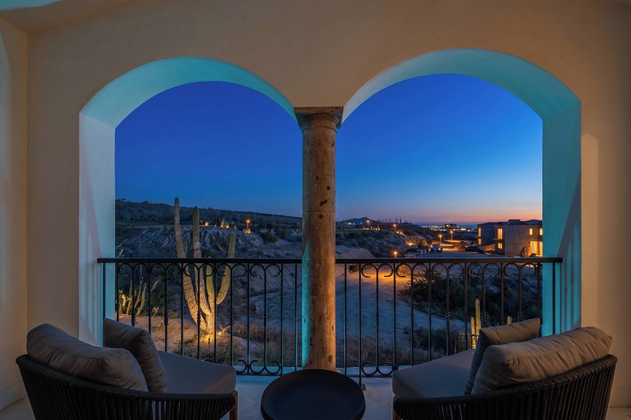 Un balcón con dos sillas y vista a un paisaje desértico al anochecer.