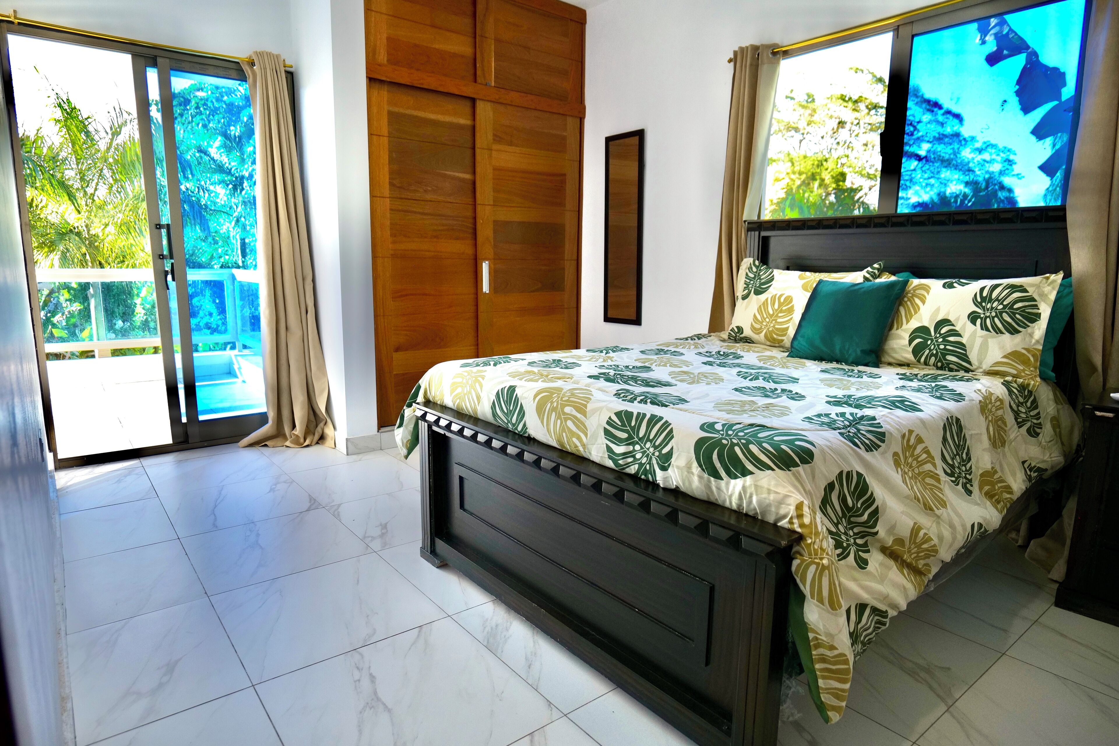 A bedroom with a bed, curtains, a wardrobe, and a TV.