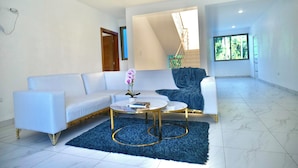 Una sala de estar moderna con un sofá blanco, una mesa de centro redonda y una alfombra azul.