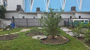 Un quartier résidentiel avec un jardin, un immeuble bleu aux encadrements de fenêtres blancs et une clôture.