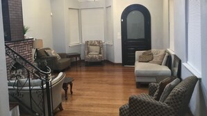Un salon avec un escalier, un lustre et une porte noire.
