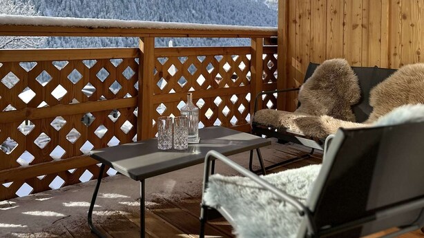 A balcony with a wooden lattice, a table with glasses, and a chair with a fur throw. - Cozy T2 and mountain area, a stone's throw from the slopes! (CHATEL)