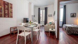 Une pièce moderne et bien éclairée, comprenant un coin repas, un canapé et un lit.