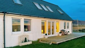 Ein zweigeschossiges Haus mit einer Holzdiele, großen Fenstern und einem Schornstein.