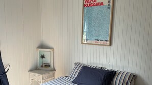 A bedroom with a bed, a nightstand, and a wall-mounted poster. - Quintessential Tassie Shack (South Mount Cameron)