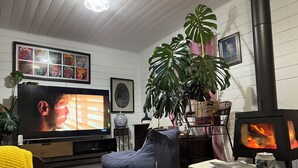A cozy living room with a television, a fireplace, and a comfortable seating area. - Quintessential Tassie Shack (South Mount Cameron)
