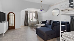 A spacious living room with a sofa, a TV, a dining area, and a bunk bed. - HernöRum - Storgatan (Harnosand)