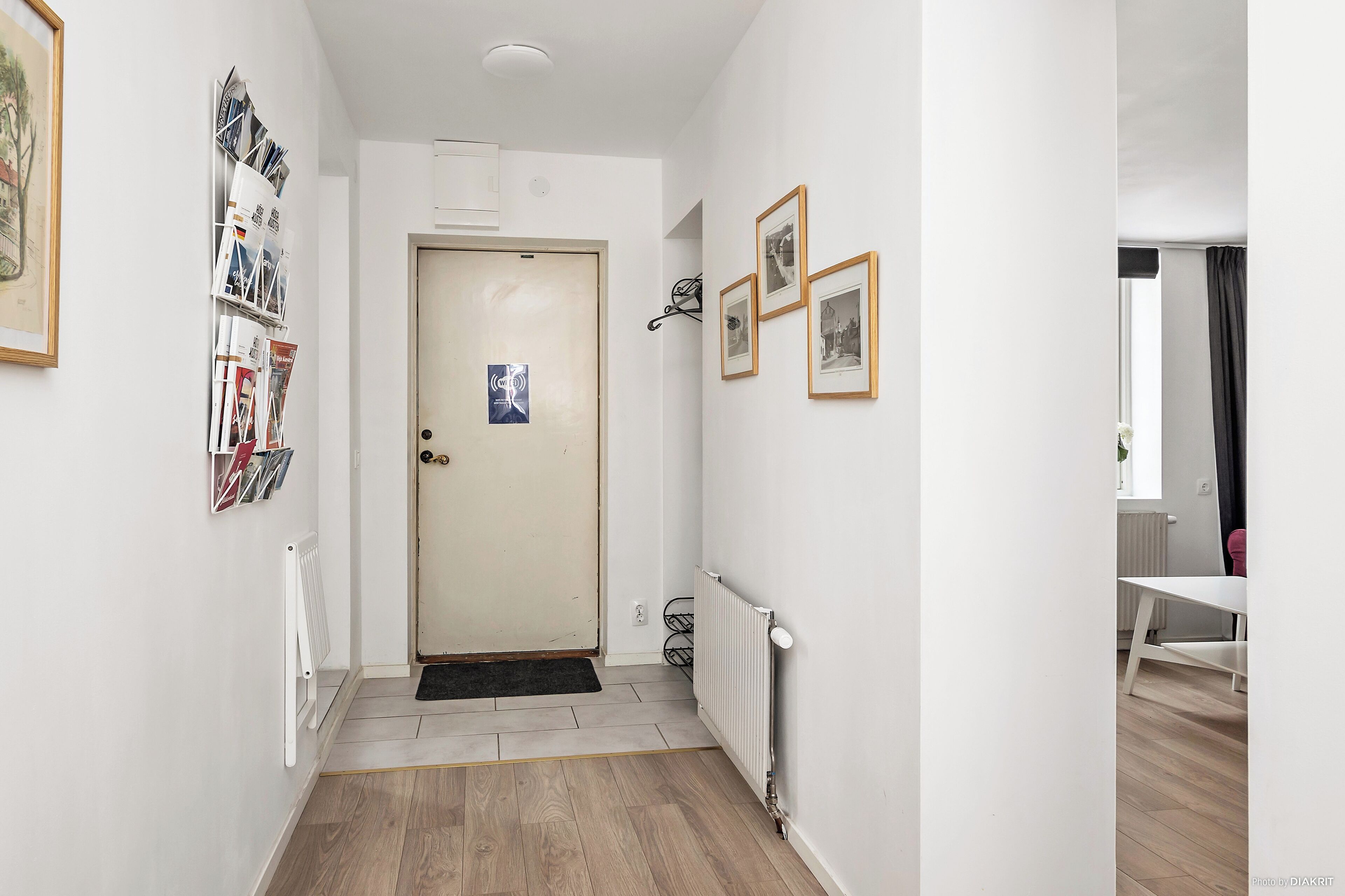 Un couloir avec un radiateur, une porte et une petite table dans un coin.