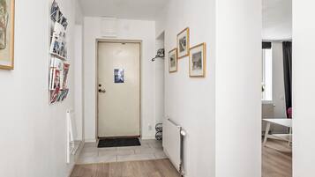 Un couloir avec un radiateur, une porte et une petite table dans un coin.