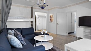 A modern living room with a sofa, a round coffee table, a TV, and a bunk bed. - HernöRum - Storgatan (Harnosand)