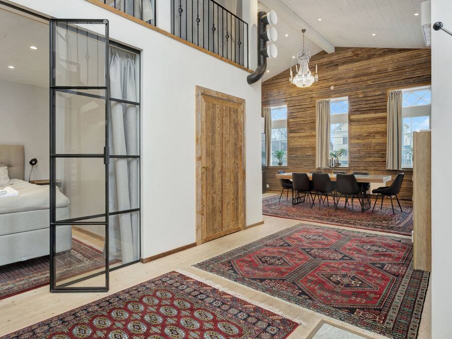 A modern interior with a bed, a dining area, and a staircase.