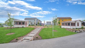 A row of single-story houses with a central walkway, surrounded by well-maintained lawns and small trees.