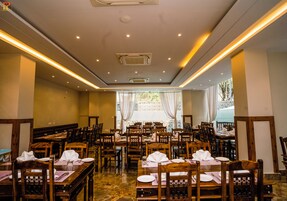 A restaurant with wooden tables and chairs, arranged in a spacious layout with a view of the outdoors.