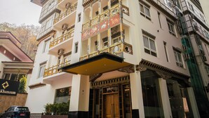 A multi-story building with balconies, a central entrance, and a sign that reads "Khamsum". - Hotel Khamsum (Phuntsholing)