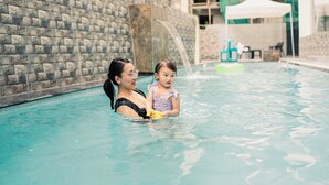 A swimming pool with stone walls and a green tent in the background. - Hotel Khamsum (Phuntsholing)