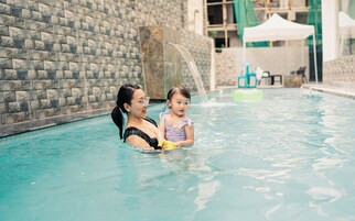 A swimming pool with a stone wall and a green tent in the background.