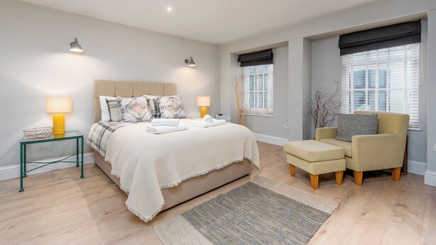 Une chambre à coucher moderne avec un lit, des tables de chevet, une chaise et une fenêtre.