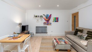 Un salon moderne avec un canapé, une table basse, un téléviseur et des œuvres d’art accrochées au mur.
