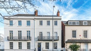 Un immeuble à plusieurs étages, doté d’une façade blanche, de nombreuses fenêtres et d’une clôture en métal noir.