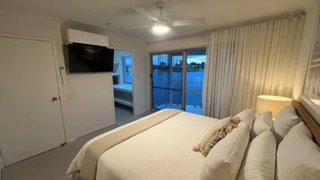Une chambre d’hôtel avec un grand lit, un ventilateur de plafond, un téléviseur fixé au mur et une vue sur l’extérieur grâce à une porte coulissante.