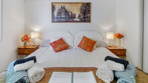 Una habitación de hotel con una cama, dos mesitas de noche, un cuadro y una ventana.
