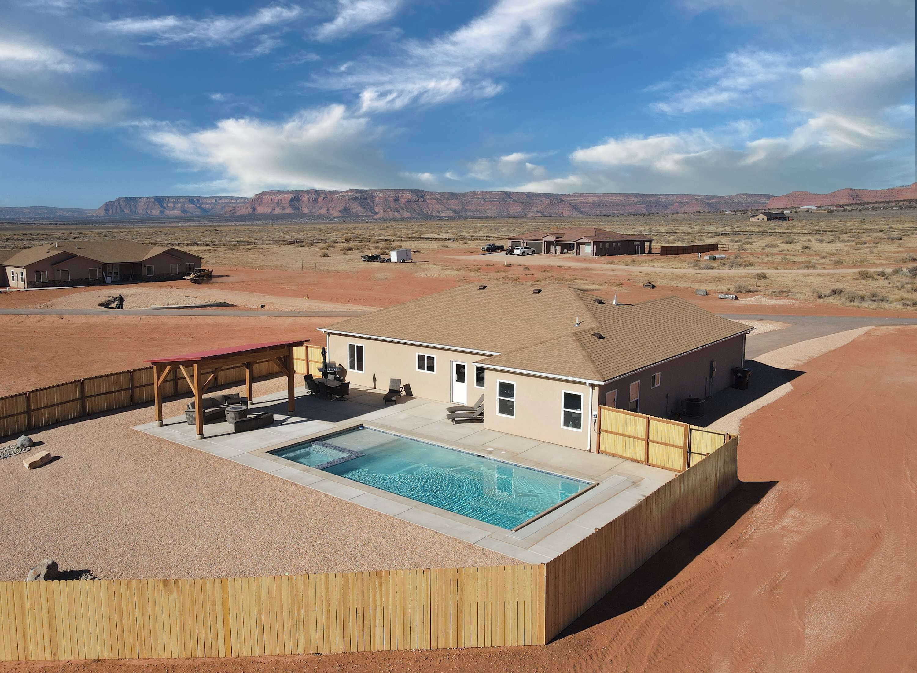 Et hus med swimmingpool, overdækket terrasse og udsigt over et ørkenlandskab.