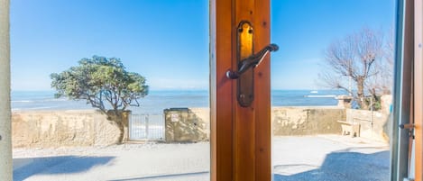 A view from a room with a wooden door leading to a beach.