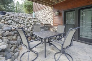 Eine Terrasse im Freien mit einer Steinmauer, einem Grill und vier Stühlen.
