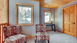 A room with two patterned armchairs, a wooden door, and a window with a view of trees. - Lakefront Gem w/ Dock & Views in Lac Du Flambeau (Lac Du Flambeau)
