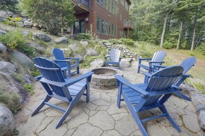 Un patio con cuatro sillas Adirondack dispuestas alrededor de un brasero.