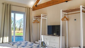 Un dormitorio con una cama grande, un televisor en una cómoda y vistas al exterior.
