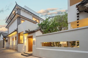 Un edificio de estilo tradicional con una entrada moderna, una escalera visible y un pequeño jardín.