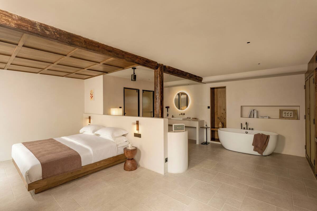 Un dormitorio moderno con una cama grande, una mesita de noche y un baño con bañera y tocador.