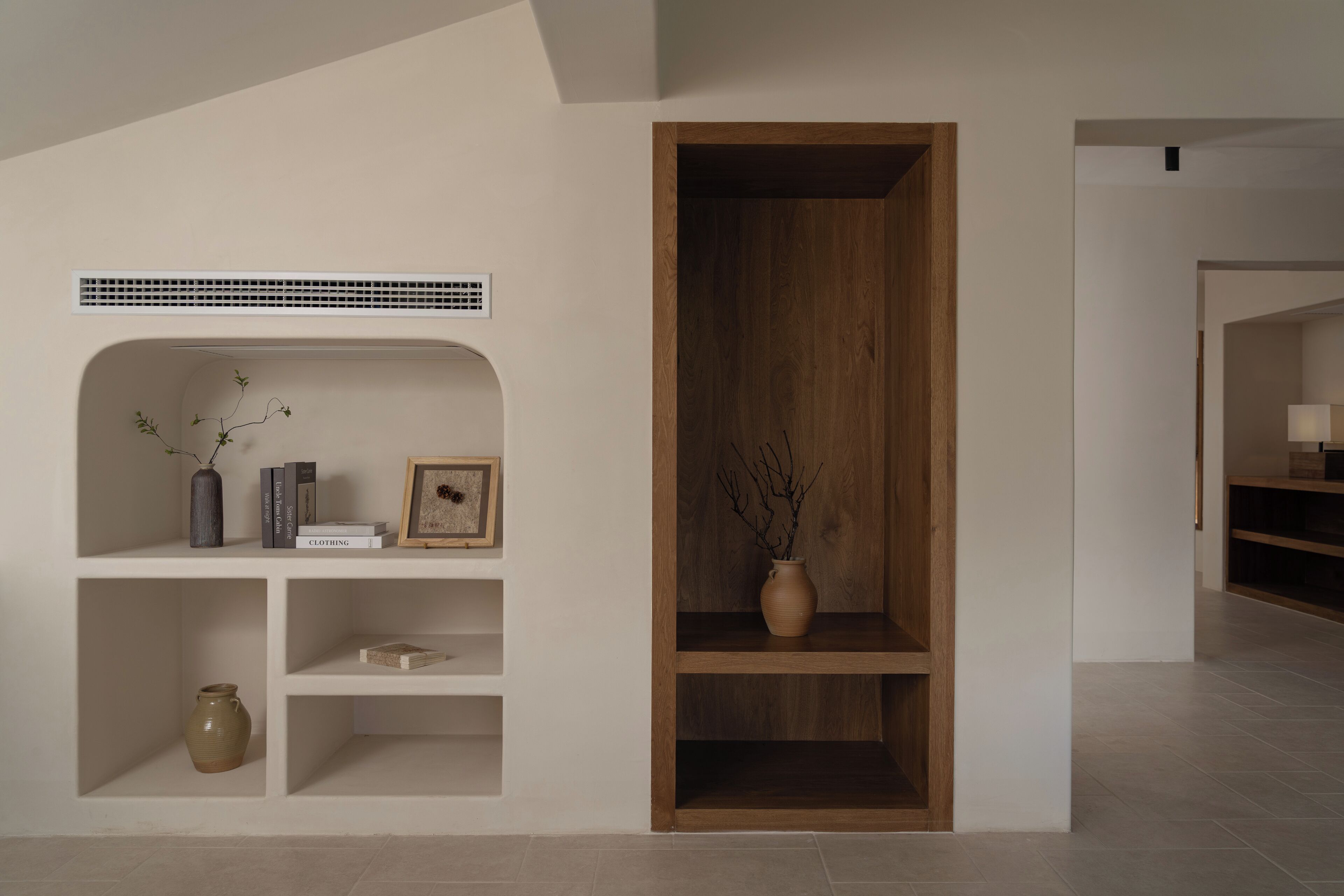 A modern interior with a white shelving unit, a wooden cabinet, and a vent on the wall.