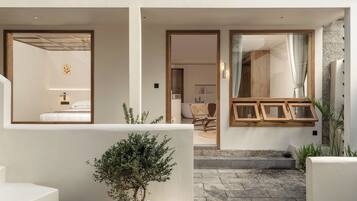 Interior de un hotel moderno con un diseño limpio y minimalista, que incluye una escalera, una pequeña planta en maceta y vistas a la habitación contigua.