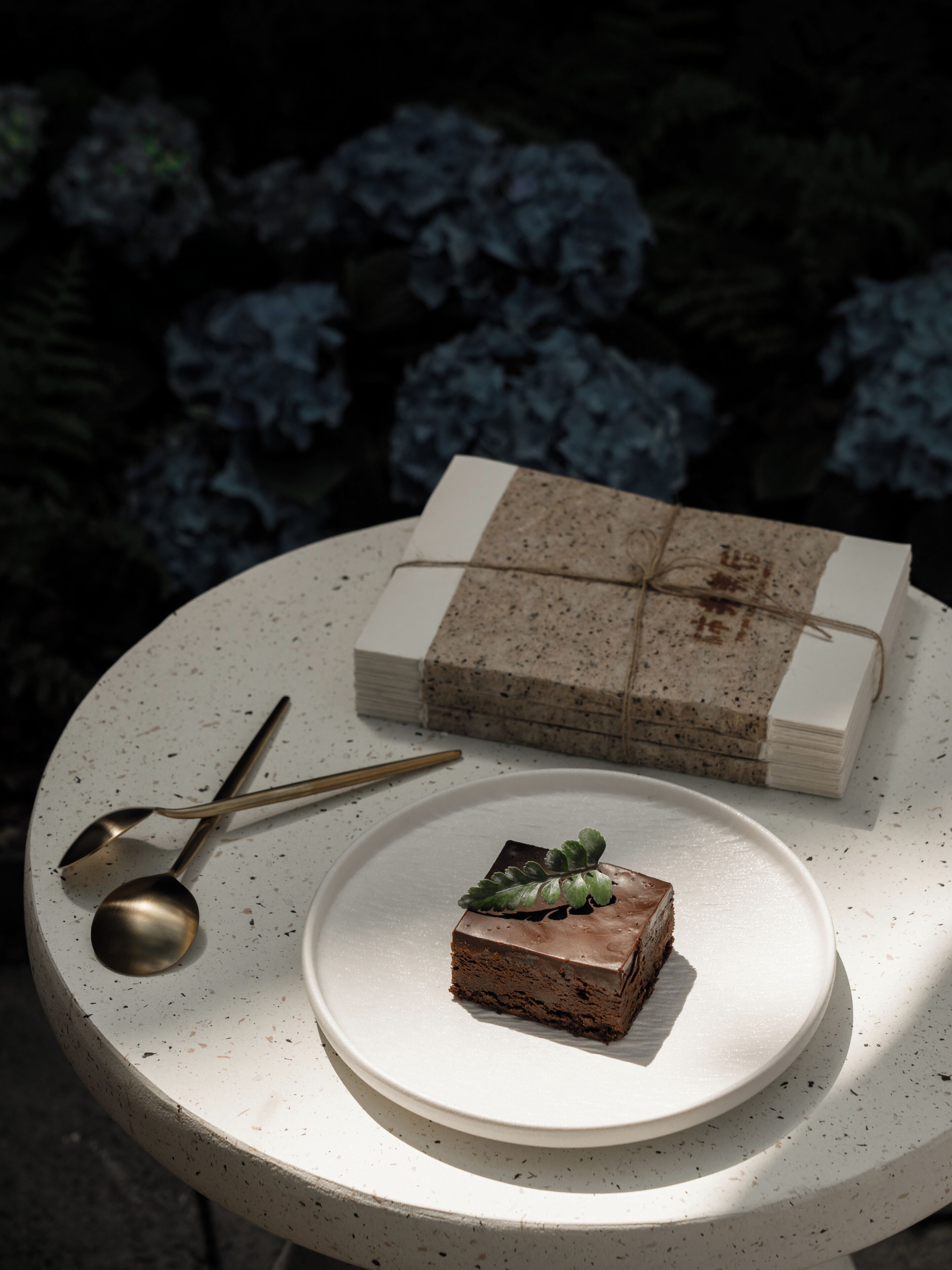A round table with a white plate holding a slice of cake and a stack of gift boxes tied with a string.