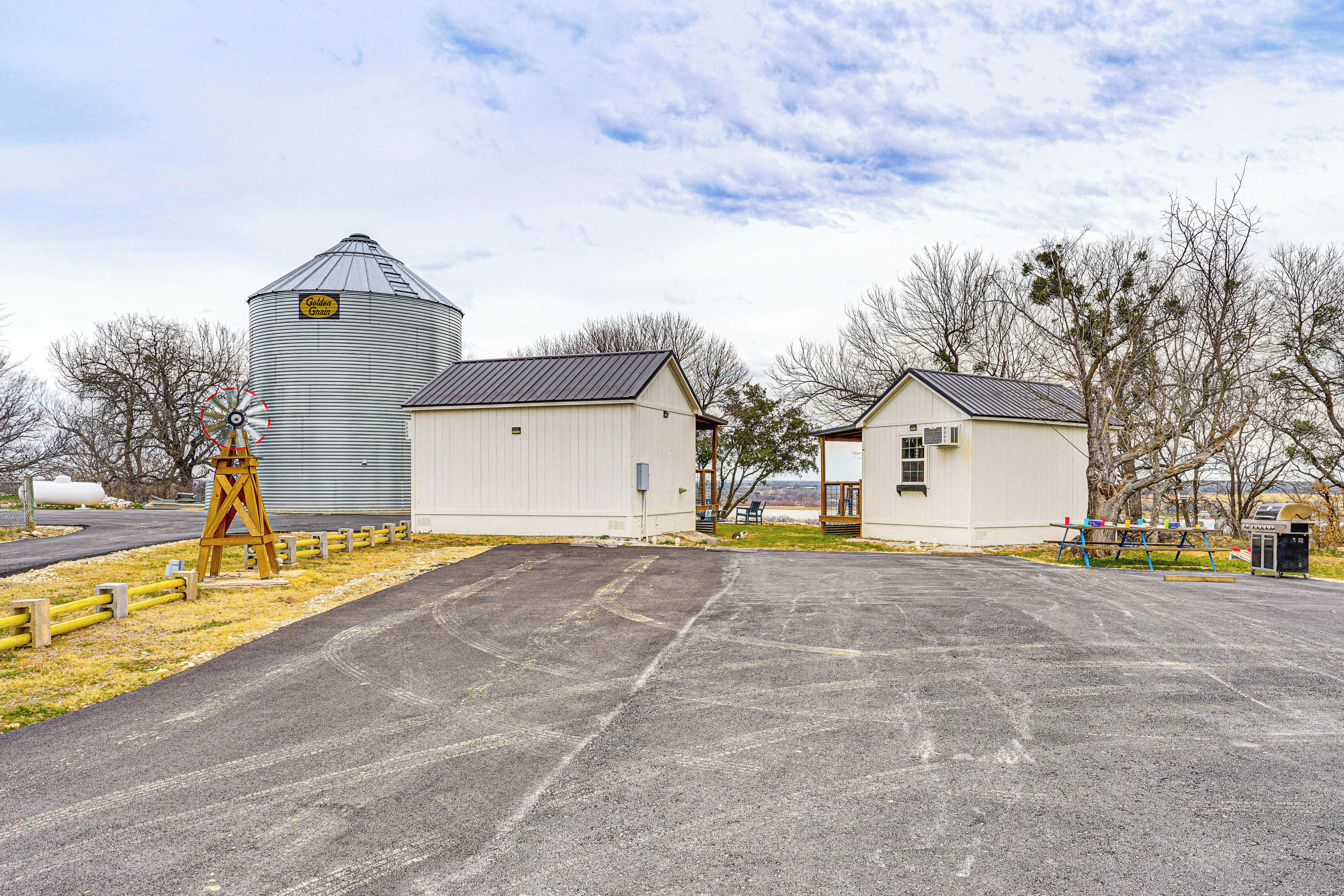 A grain silo, a small building, and a paved area with a wooden fence.
