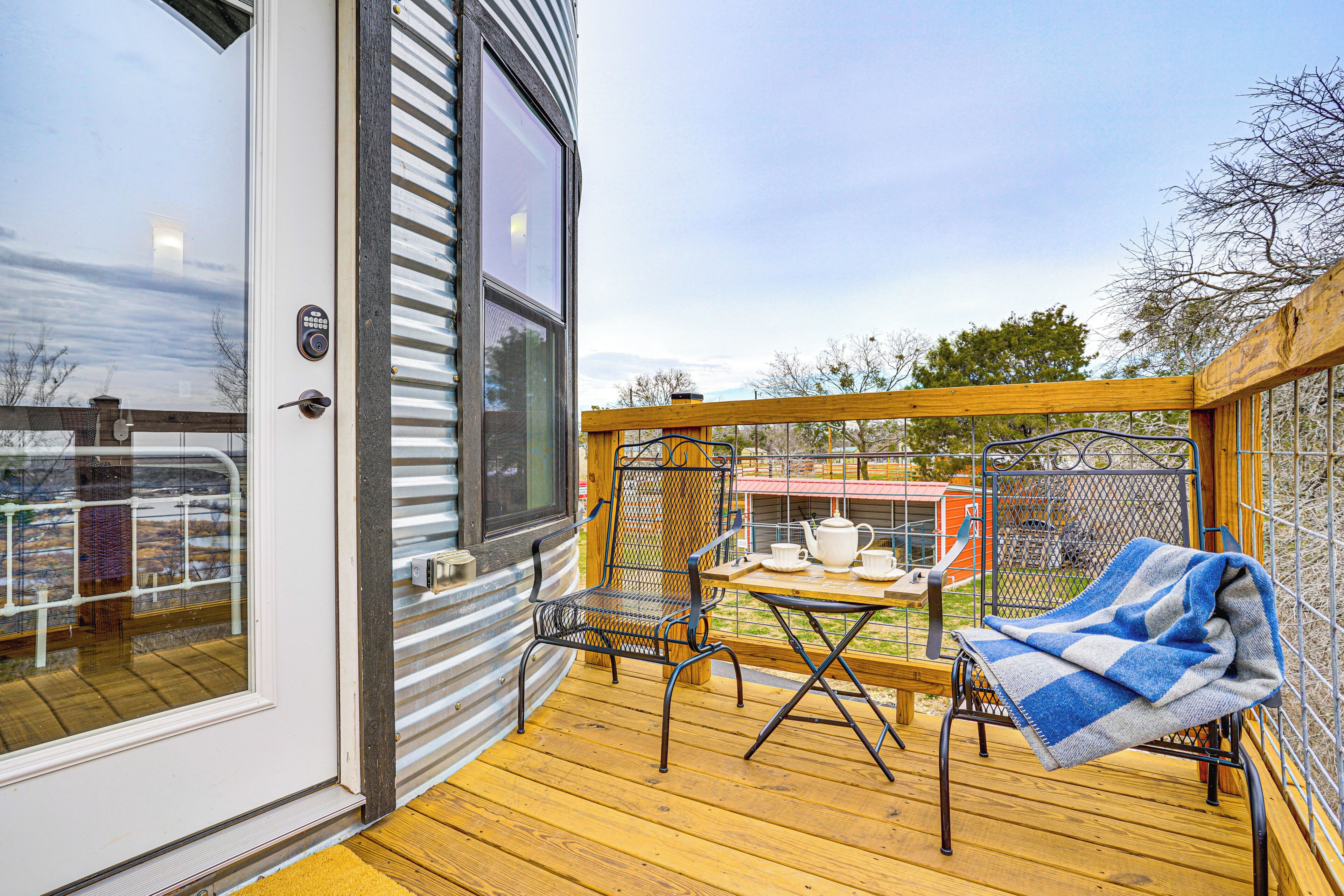 Une terrasse avec une table et des chaises, une fenêtre et une porte.