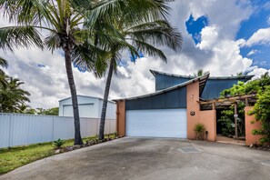 A modern house with a garage, palm trees, and a clear sky. - Dolphin Dreamin' with magnesium pool (Agnes Water)