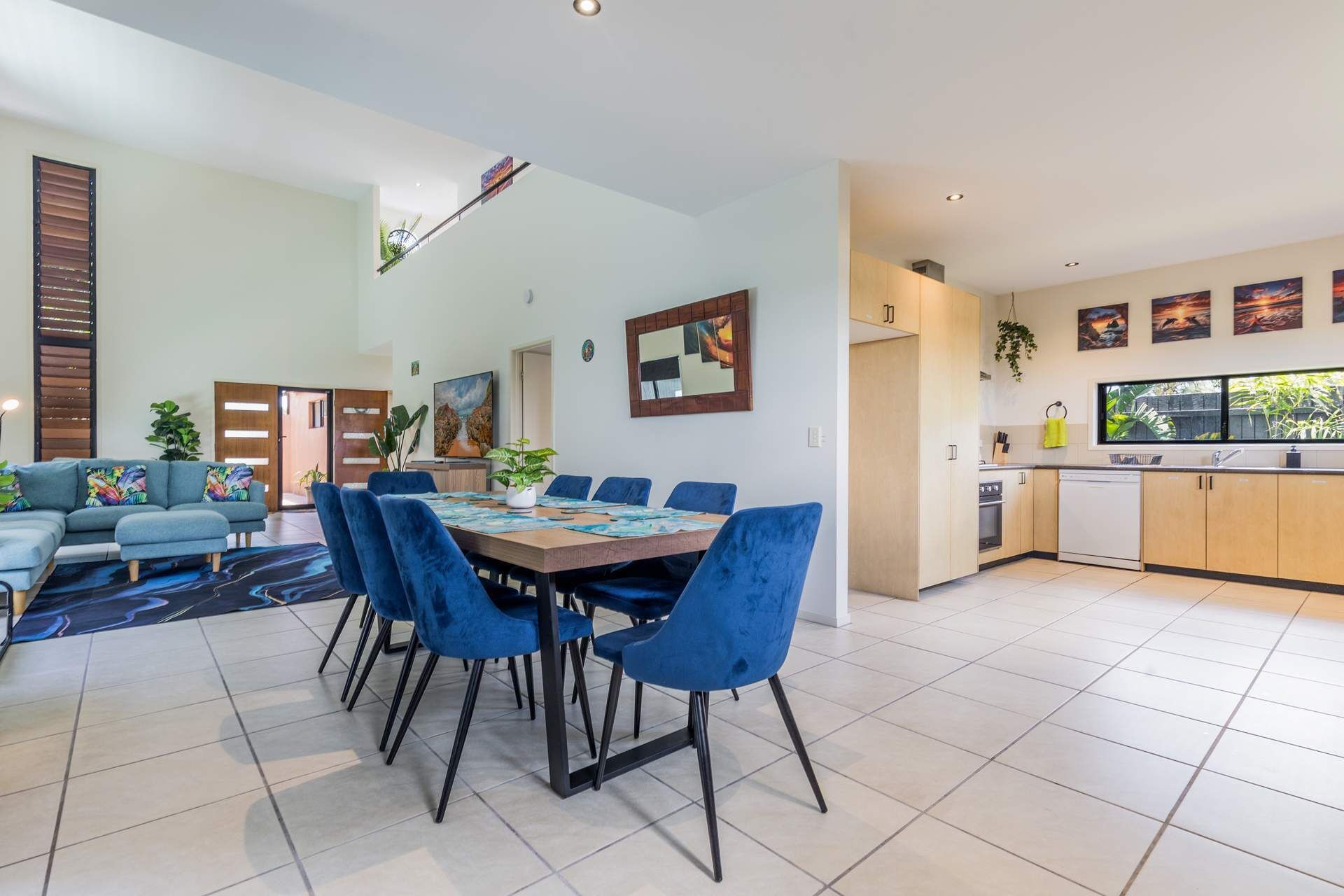 A modern living space with a dining area, kitchen, and a large window.