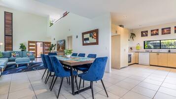 A modern living space with a dining area, kitchen, and a large window.