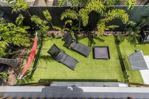 A rooftop garden with artificial grass, four lounge chairs, a hammock, and various tropical plants. - Dolphin Dreamin' with magnesium pool (Agnes Water)