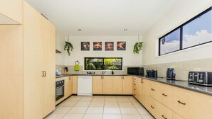 Una cocina moderna con armarios de madera, lavavajillas, estufa y un amplio ventanal con vistas al verdor.