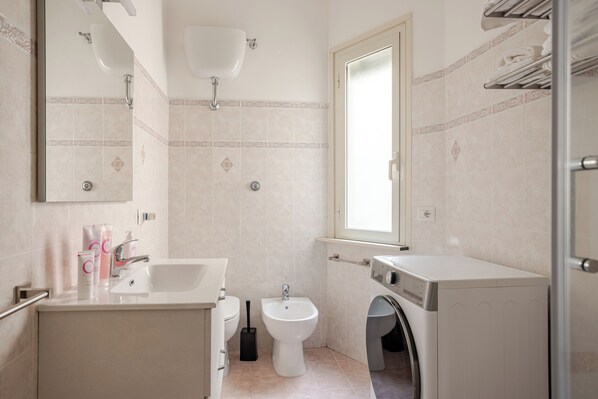 A modern bathroom with a sink, bidet, and washing machine.