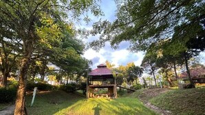 A gazebo in a park with a grassy path leading to it, surrounded by trees. - Petpumok Wangnamkhiao Hotel (Wang Nam Khiao)