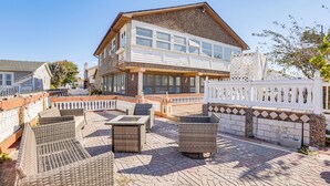 A two-story building with a balcony and outdoor seating area. - Beachfront Home ~ 7 Mi to Cape May! (Villas)