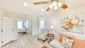 Una habitación amplia con ventilador de techo, una cama, un sofá y un cuadro en la pared.