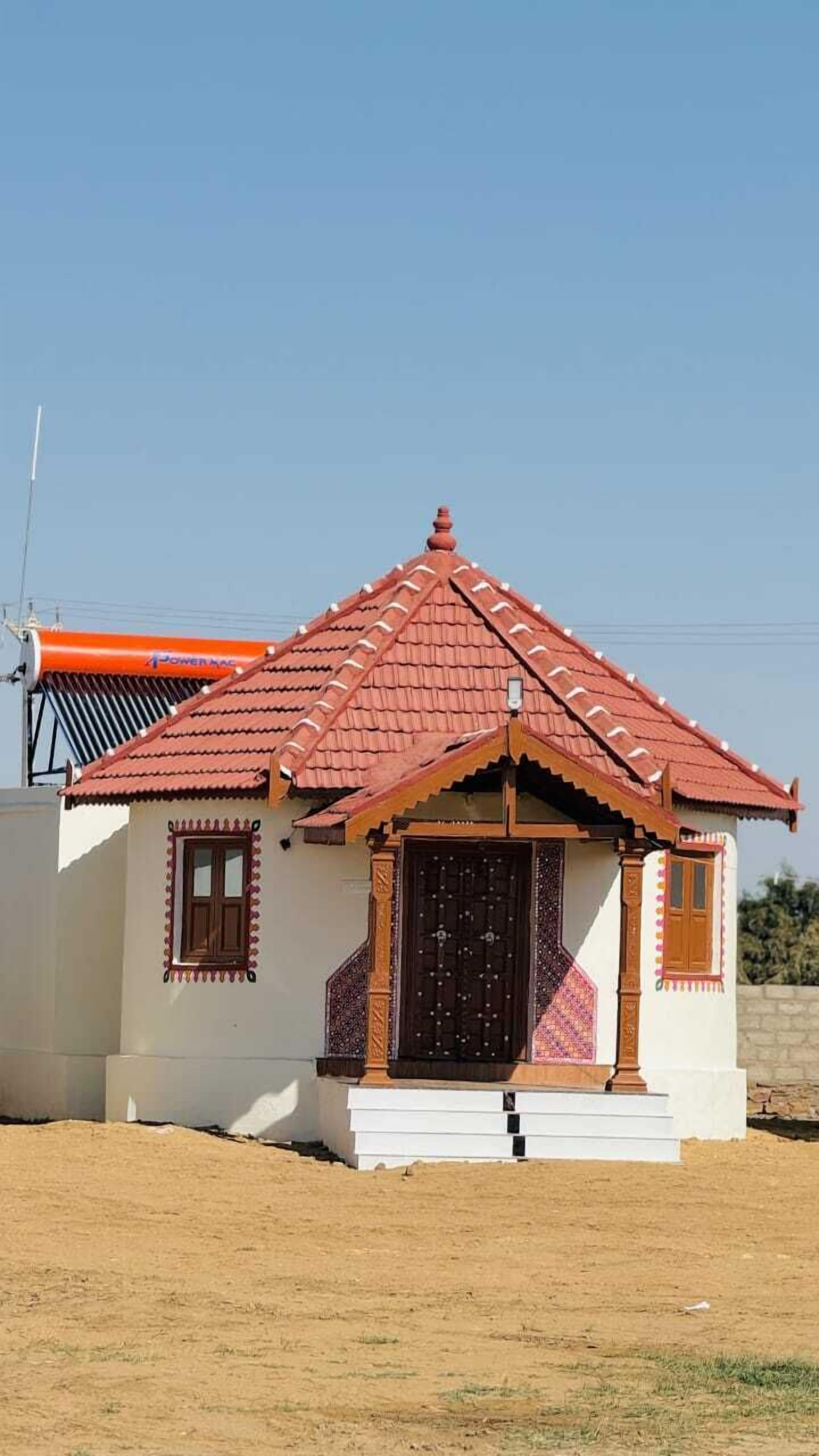Una piccola casa a un piano con tetto in tegole rosse e un'apertura centrale.