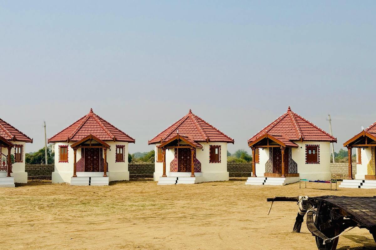 A row of small, uniformly designed houses with red-tiled roofs and white walls, each featuring a small porch and decorative wooden elements.